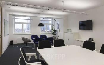 Modern conference room at Fleischmarkt 1, 1010 Vienna with a sleek white table, comfortable chairs, and a flat-screen for efficient office space rental.